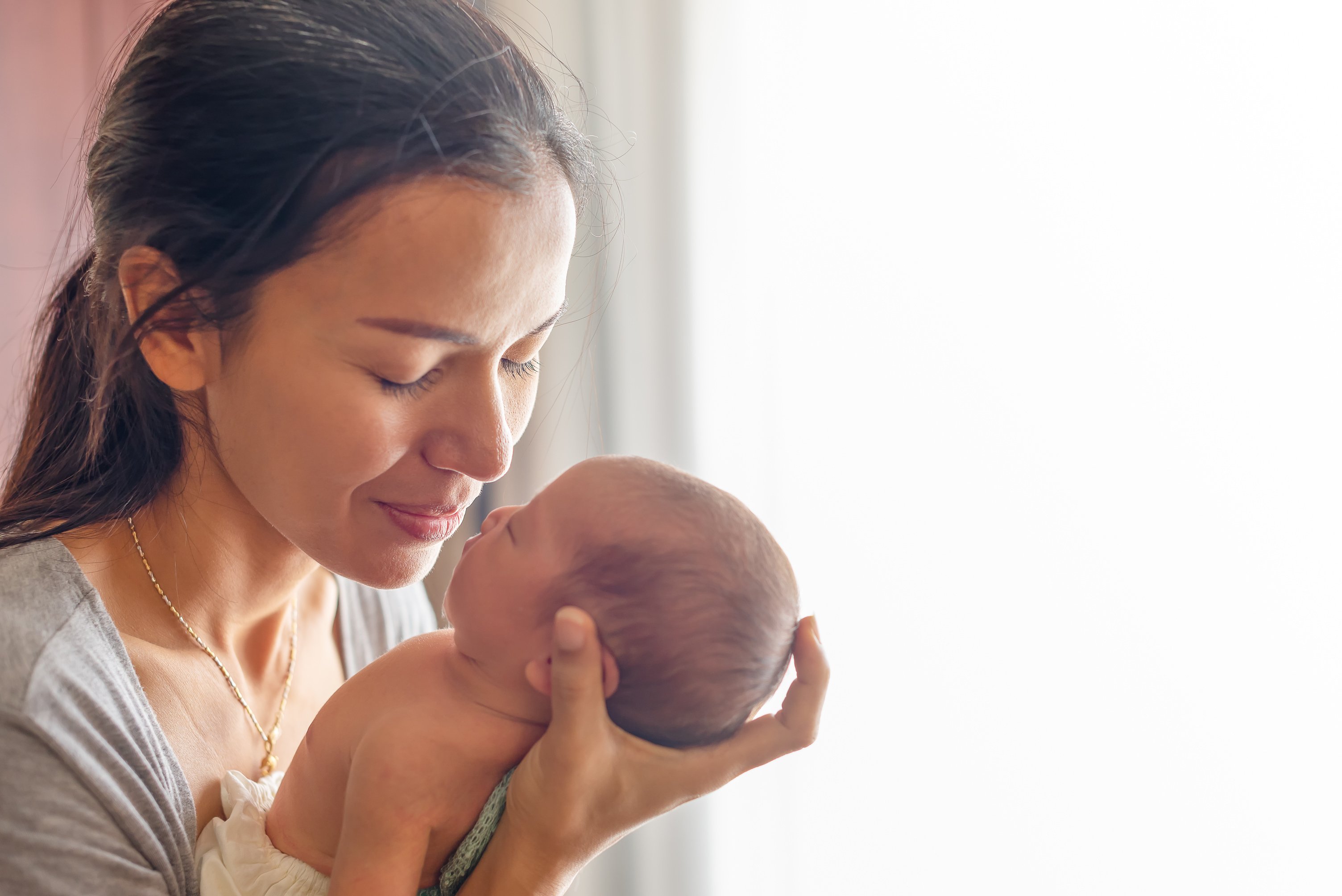 Beautiful mother kissing here little cute baby on her palm. Mother take care her little girl at home. One week newborn girl.